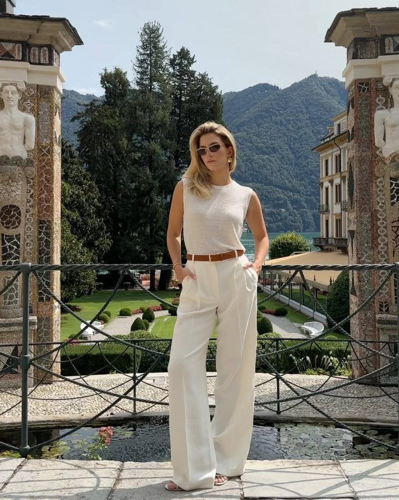 Old money summer outfit with cream sleeveless ribbed tank top, white wide-leg trousers, brown leather belt, slim rectangular sunglasses and subtle gold jewelry
