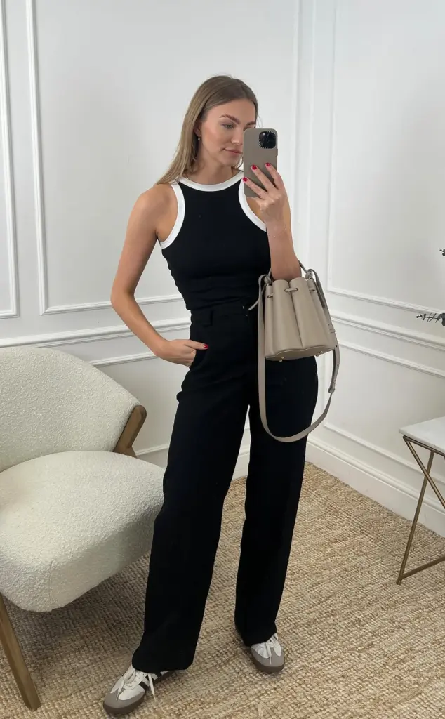 summer work outfit with black contrast-trim tank top, matching wide-leg trousers, beige bucket bag and white athletic sneakers
