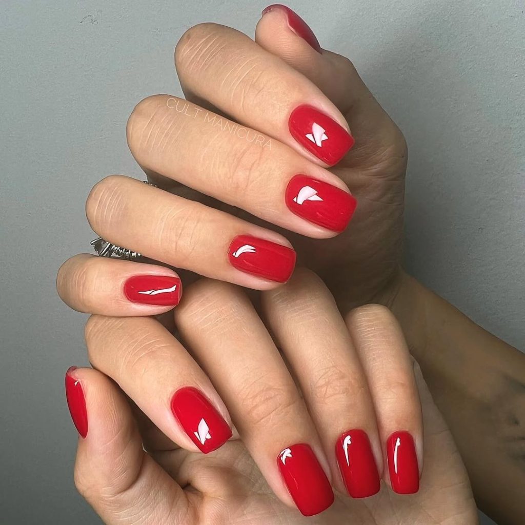 Short squoval shaped nails with bright true red polish
