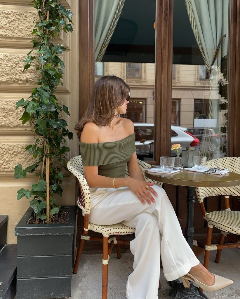 Old money summer outfit with olive green off-shoulder ribbed top, white wide-leg trousers, cream pointed mules and minimal gold jewelry
