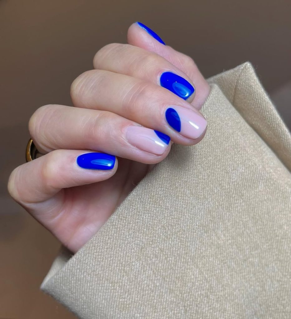 Short oval nails with electric blue solid color and two geometric accent nails for bold summer style
