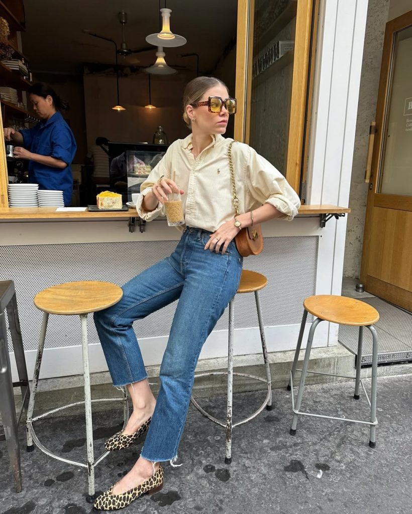 Summer outfit with cream striped button-up shirt, raw-hem straight leg jeans, leopard print flats, brown crossbody bag and oversized yellow sunglasses
