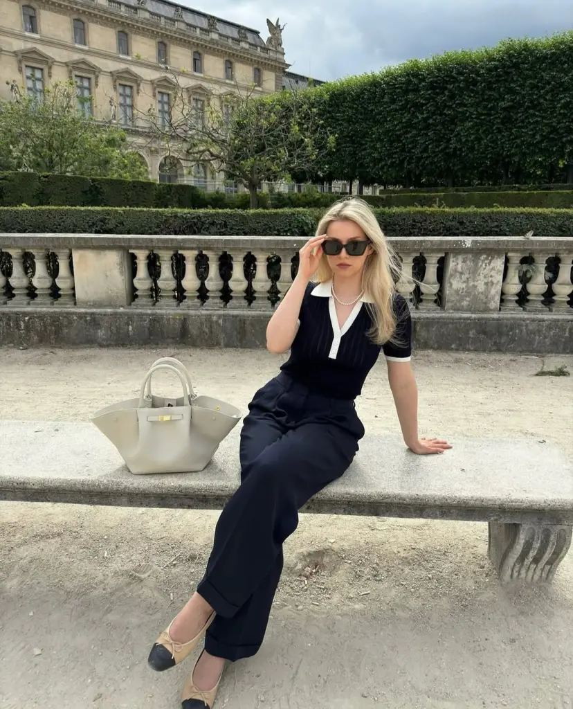 summer work outfit with navy contrast-collar polo shirt, navy tailored trousers, pearl necklace, cream structured tote and two-tone ballet flats
