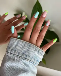 Long square nails in pastel mint, neon lime tips and pink base with abstract designs for tropical summer vibe