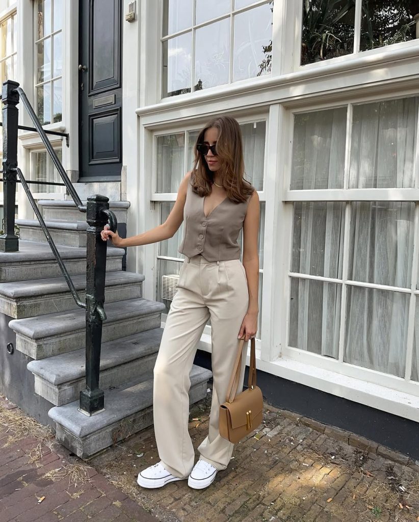 Casual summer outfit with beige button-front vest, cream wide-leg trousers, black sunglasses, tan leather crossbody bag and white platform sneakers