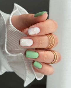 Classy short summer nails featuring white base with delicate palm leaf design and mint green accent nails