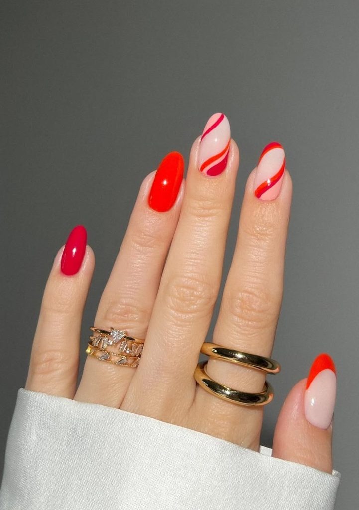 Almond neon coral-red nails with curved line designs on natural base for vibrant summer style

