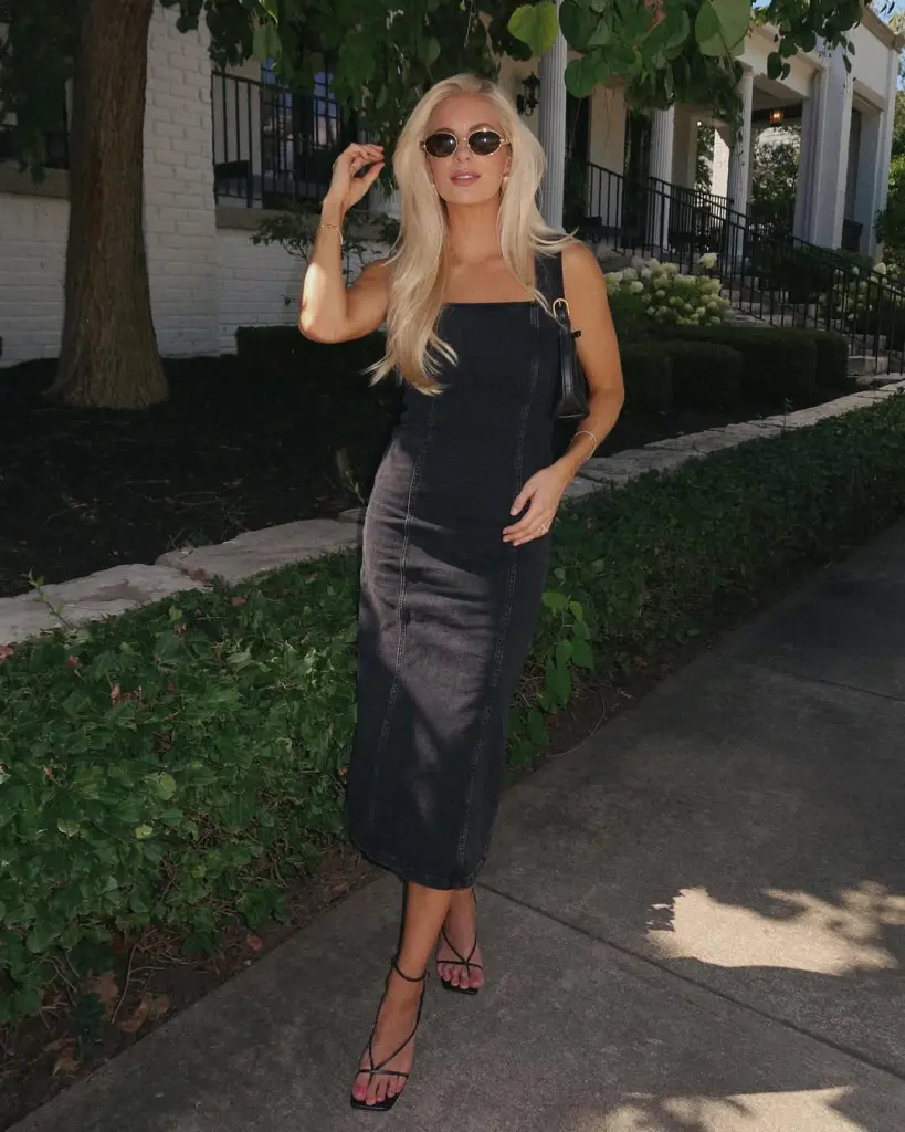 Chic summer date night outfit with fitted black denim midi dress, square neckline, sleek strappy black heels, vintage-inspired oval sunglasses and minimal gold jewelry
