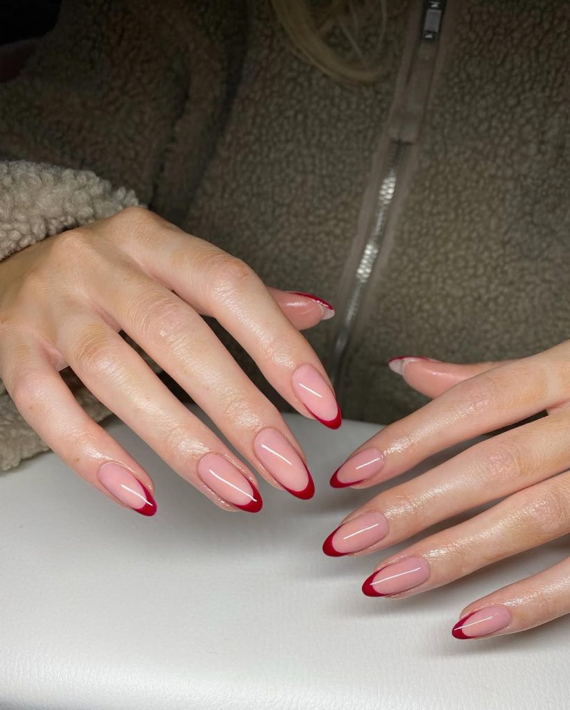 Almond shaped pink-nude nails with glossy ruby-red French tips
