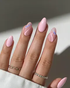 Long almond July nails with solid baby pink and milky pink base with blue dotted wave accent designs
