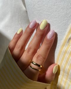 Elegant short summer nails alternating between soft yellow and milky white polish with gold shimmer accents