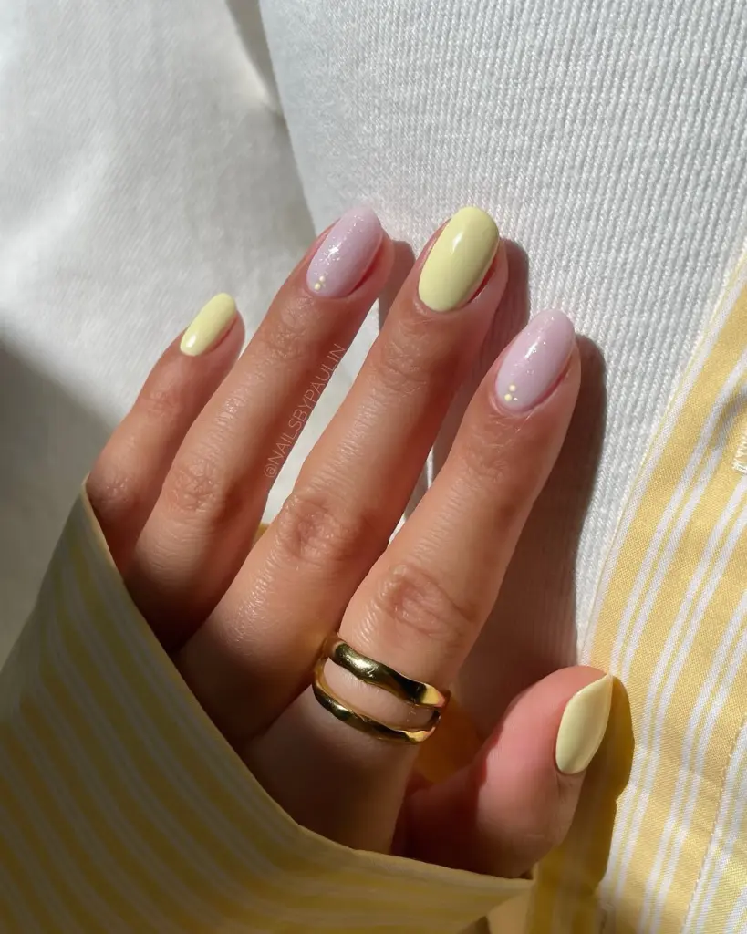Elegant short summer nails alternating between soft yellow and milky white polish with gold shimmer accents