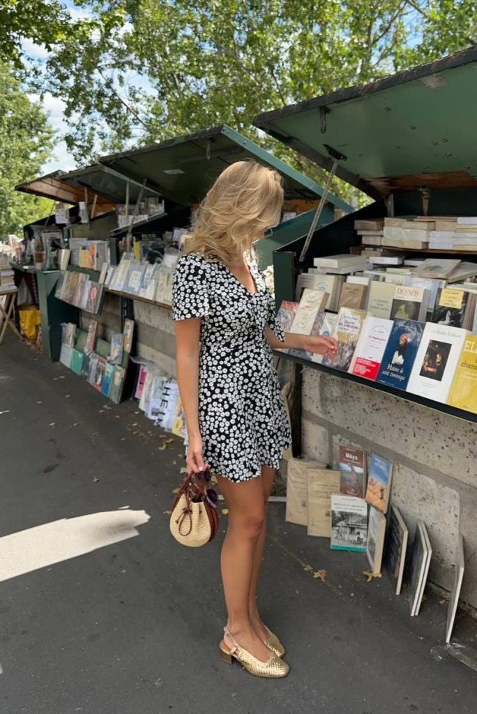 Parisian summer outfit with black and white daisy print mini dress, gold woven slingback flats and round straw handbag