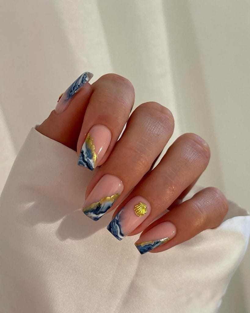 square vacation nails with blue wave nail art gold foil and seashell charm accents