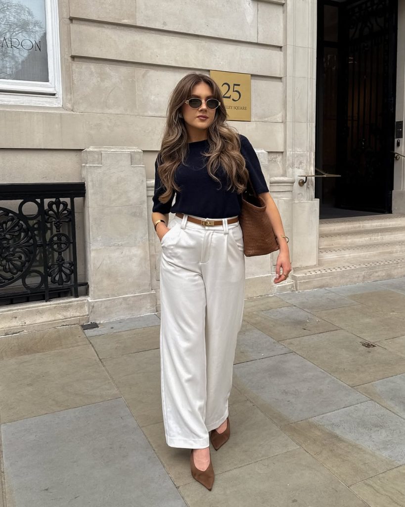 summer work outfit with navy top, white tailored trousers, thin white belt, brown suede pumps and woven shoulder bag
