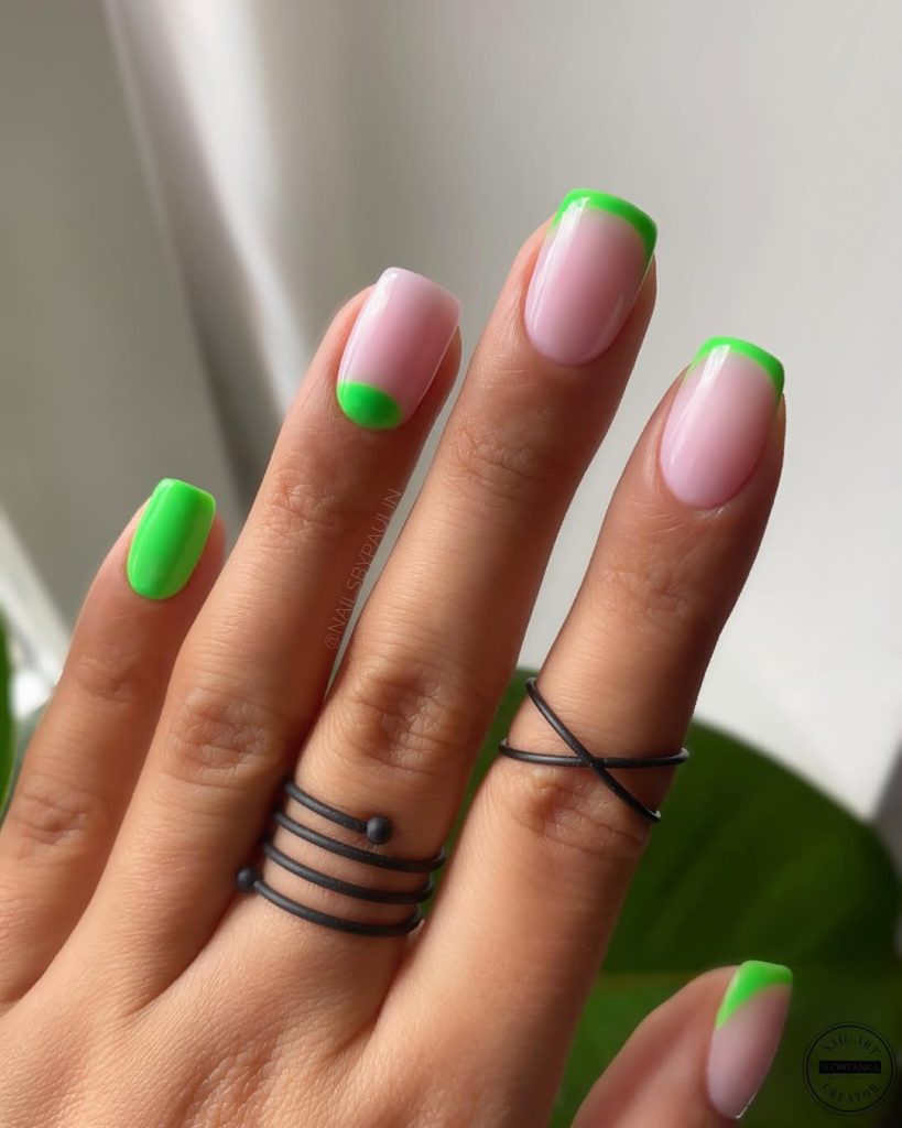 Short milky pink nails with neon lime green French tips, half-moon, and accent nail for bright summer manicure
