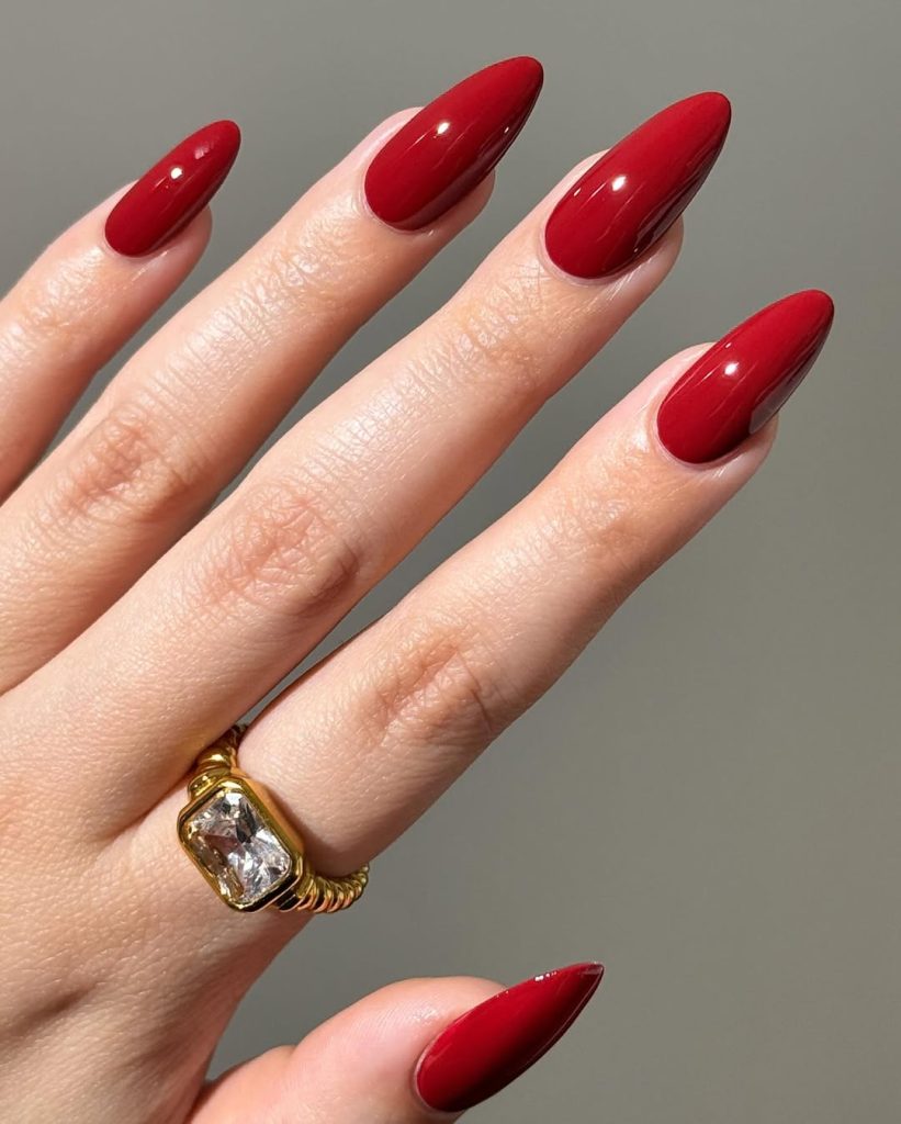 Almond shaped nails with deep crimson red polish and high-gloss finish