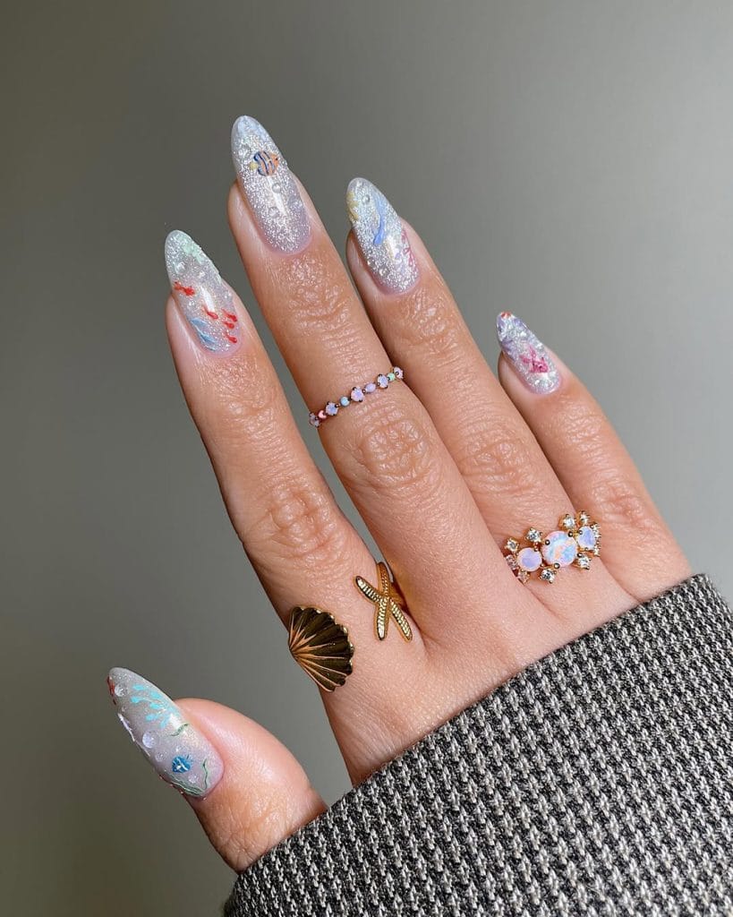 Long almond vacation nails with clear glitter base and colorful sea life nail art designs
