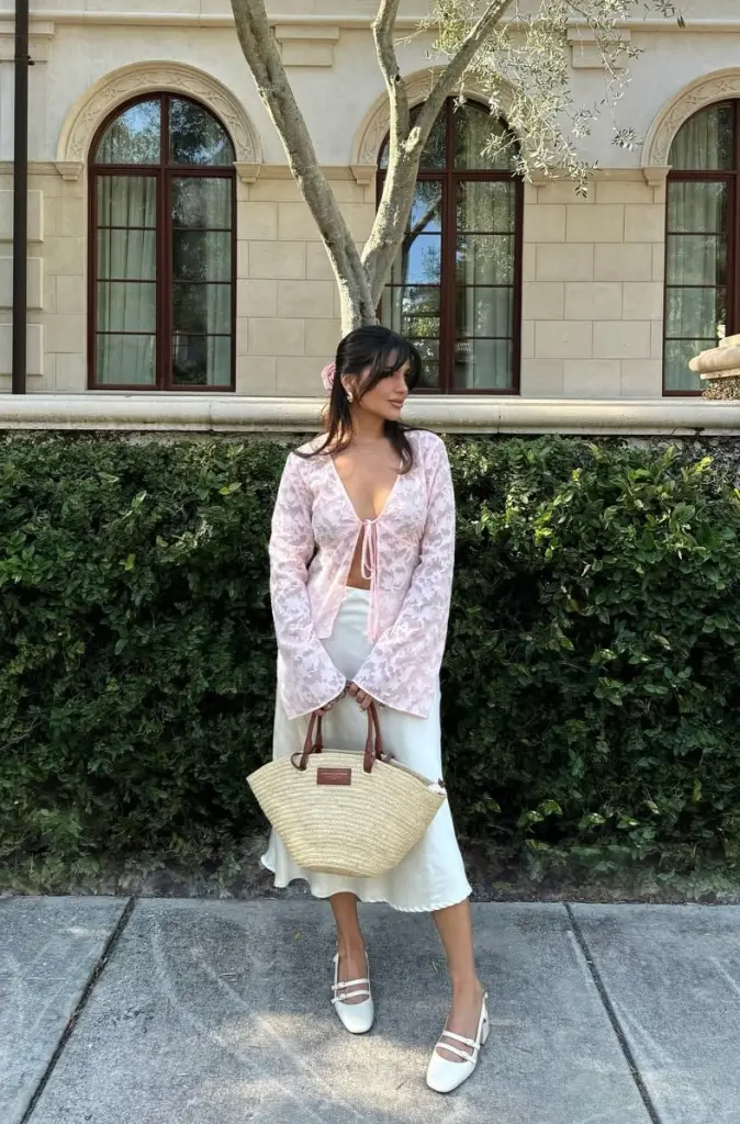 summer date night outfit with sheer pink floral tie-front blouse, flowing cream satin midi skirt, white Mary Jane heels and natural straw handbag
