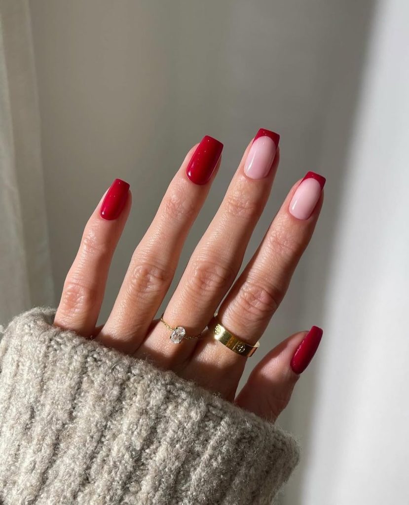Square shaped nails with alternating solid magenta-red polish and sheer pink nails with bright red French tips

