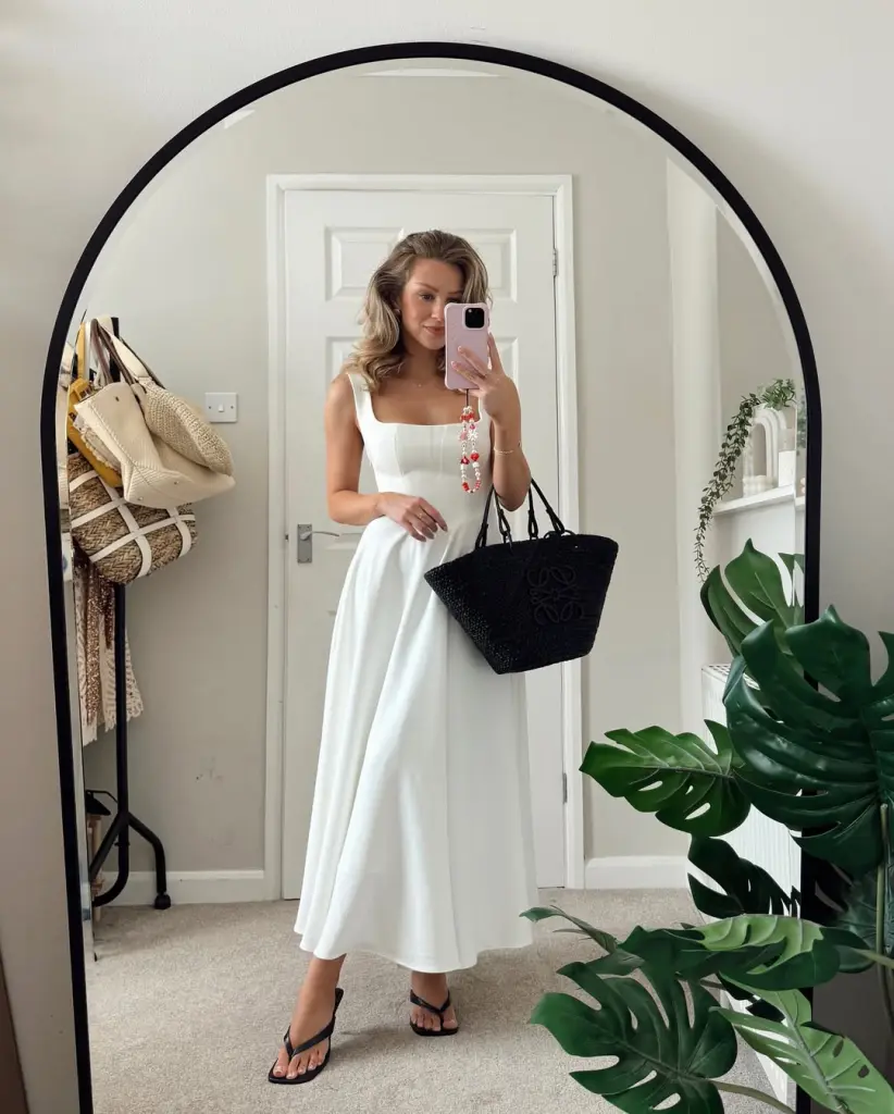Effortless summer date night outfit with white square-neck midi dress, fitted bodice, flowy skirt, black minimalist thong sandals and structured black basket bag
