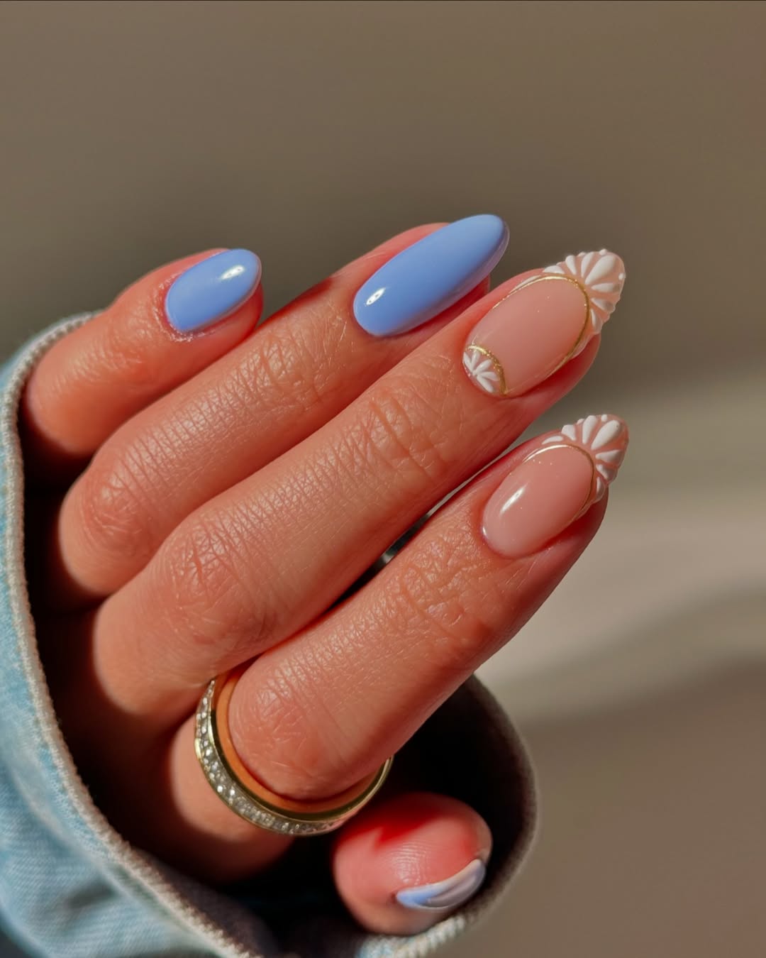 oval vacation nails with blue and nude skittles design and white daisy nail art accents