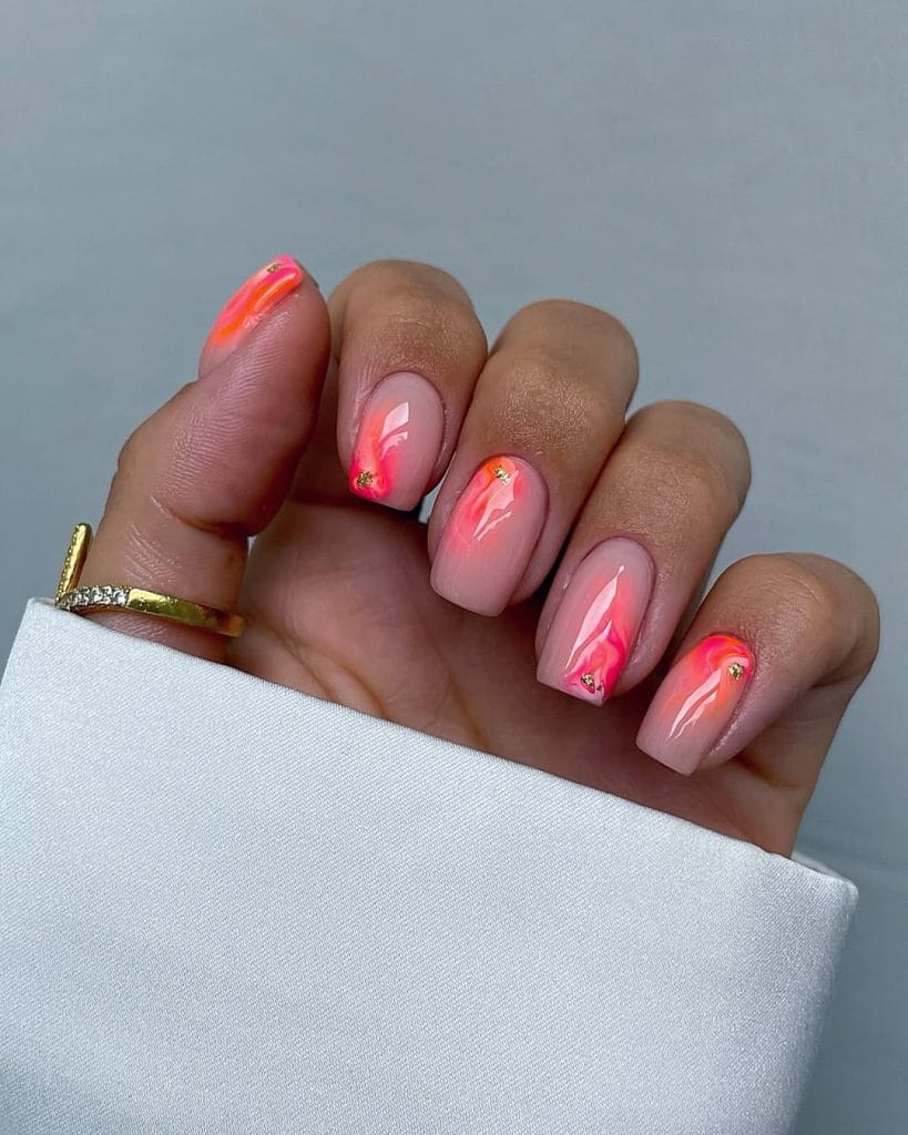 Elegant short summer nails with nude base featuring vibrant coral-pink abstract brushstroke design and gold accent details
