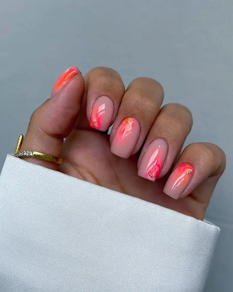 Elegant short summer nails with nude base featuring vibrant coral-pink abstract brushstroke design and gold accent details
