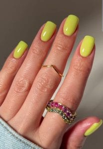Classy short summer nails with vibrant chartreuse yellow-green polish, elegant glossy finish on squared oval shape