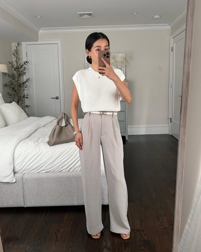 summer work outfit with white ribbed cap-sleeve top, light gray pleated trousers, slim white belt, taupe handbag and nude heeled sandals