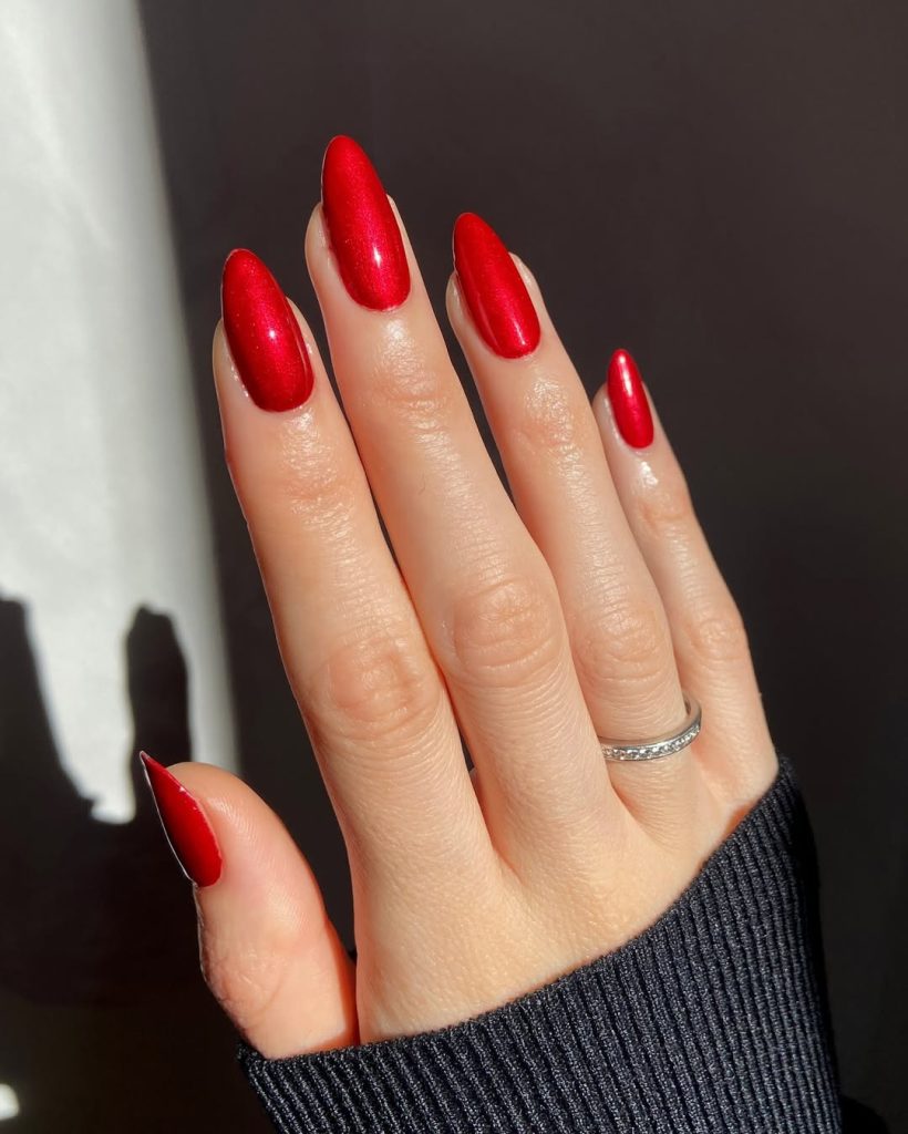 Almond shaped nails with metallic ruby-red polish with shimmer finish
