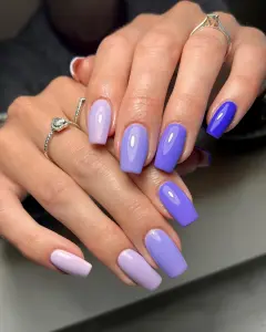Long square July nails with purple ombre gradient from light lavender to deep royal purple across different nails
