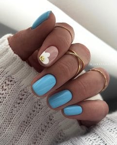 Elegant short summer nails with sky blue polish and nude accent featuring white daisy with gold center