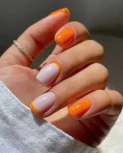 Short nails with shimmery neon orange and milky base with orange French tips