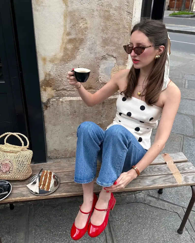 Parisian summer outfit with white and black polka dot sleeveless top, medium wash straight leg jeans, red patent mary jane heels, straw bag and tortoise sunglasses