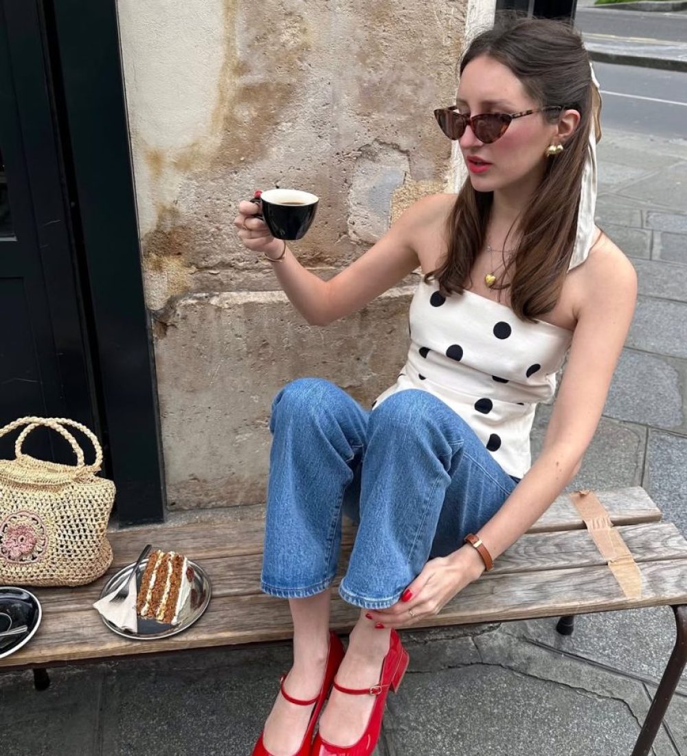 Parisian summer outfit with white and black polka dot sleeveless top, medium wash straight leg jeans, red patent mary jane heels, straw bag and tortoise sunglasses