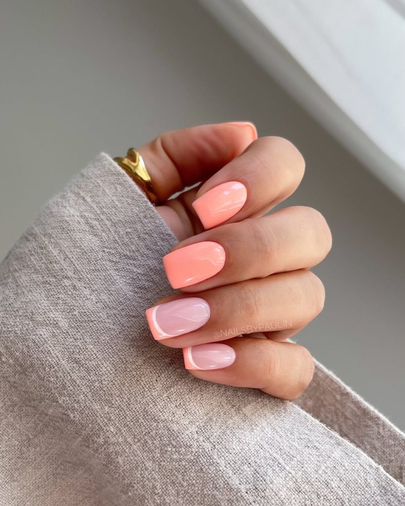 Short summer nails alternating between full coral polish and pale pink nails with coral French tips
