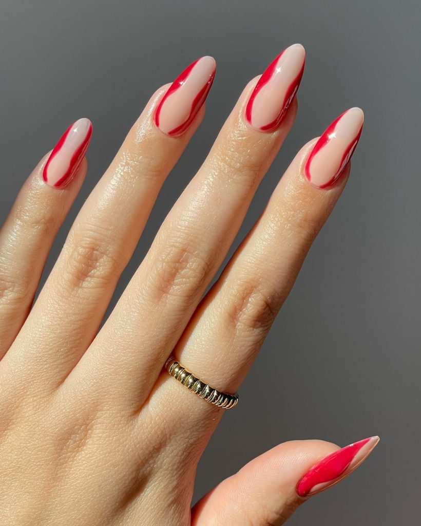  Almond shaped sheer nude nails with glossy red curved streak design along both sides