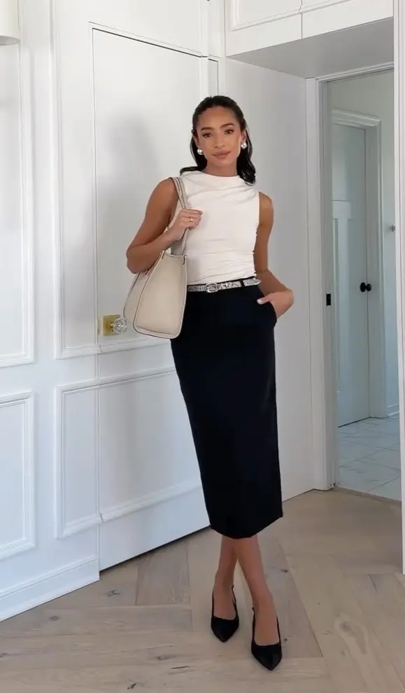 summer work outfit with white sleeveless mock neck top, black midi pencil skirt, snake-print belt, cream structured tote and black pointed heels
