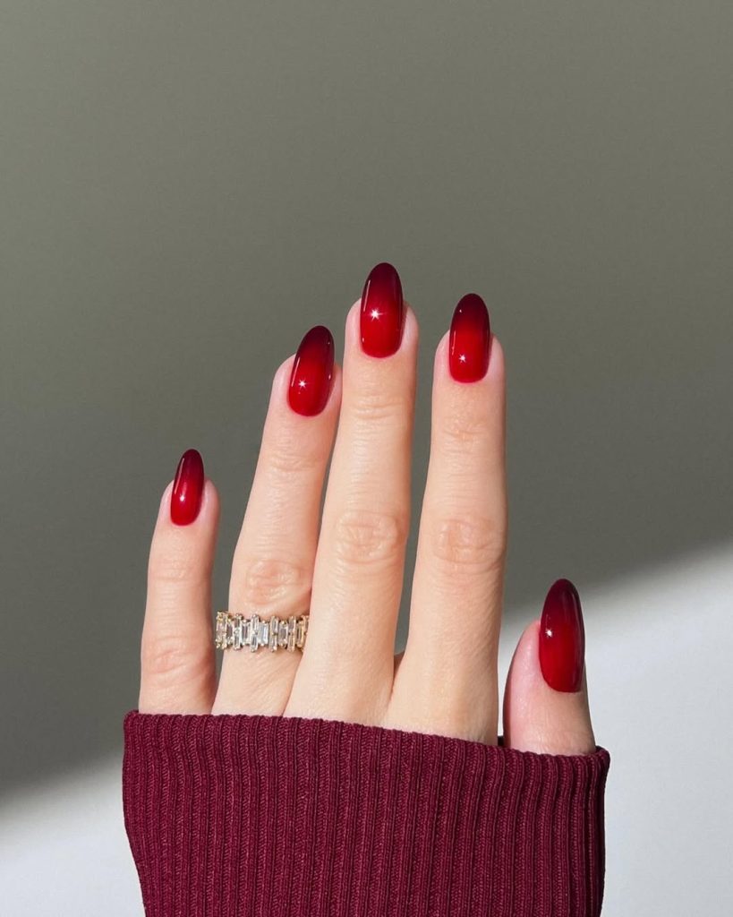 Almond shaped nails with two-tone red gradient effect showing darker burgundy at tips blending into brighter red at the base