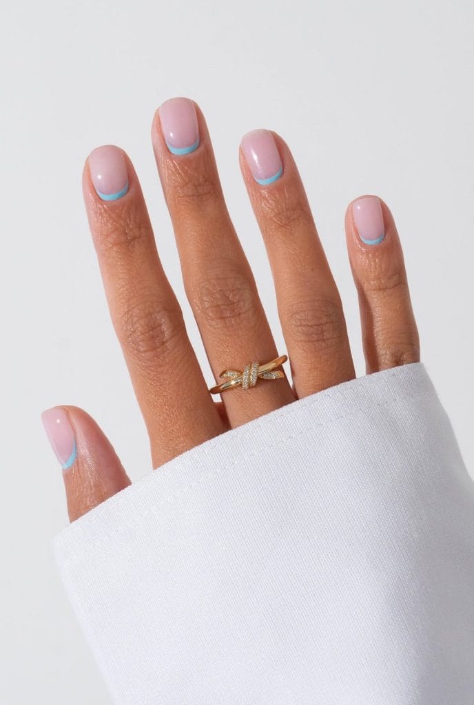 Elegant short summer nails with sheer pink base and thin baby blue French tip line
