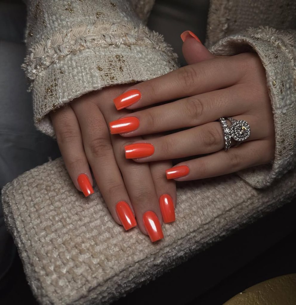 square nails in bright neon tangerine orange with glazed finish
