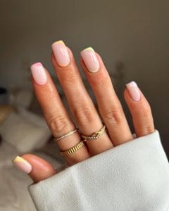 oval July nails with pink base and diagonal pastel accents along cuticles and sides in yellow, green, and purple