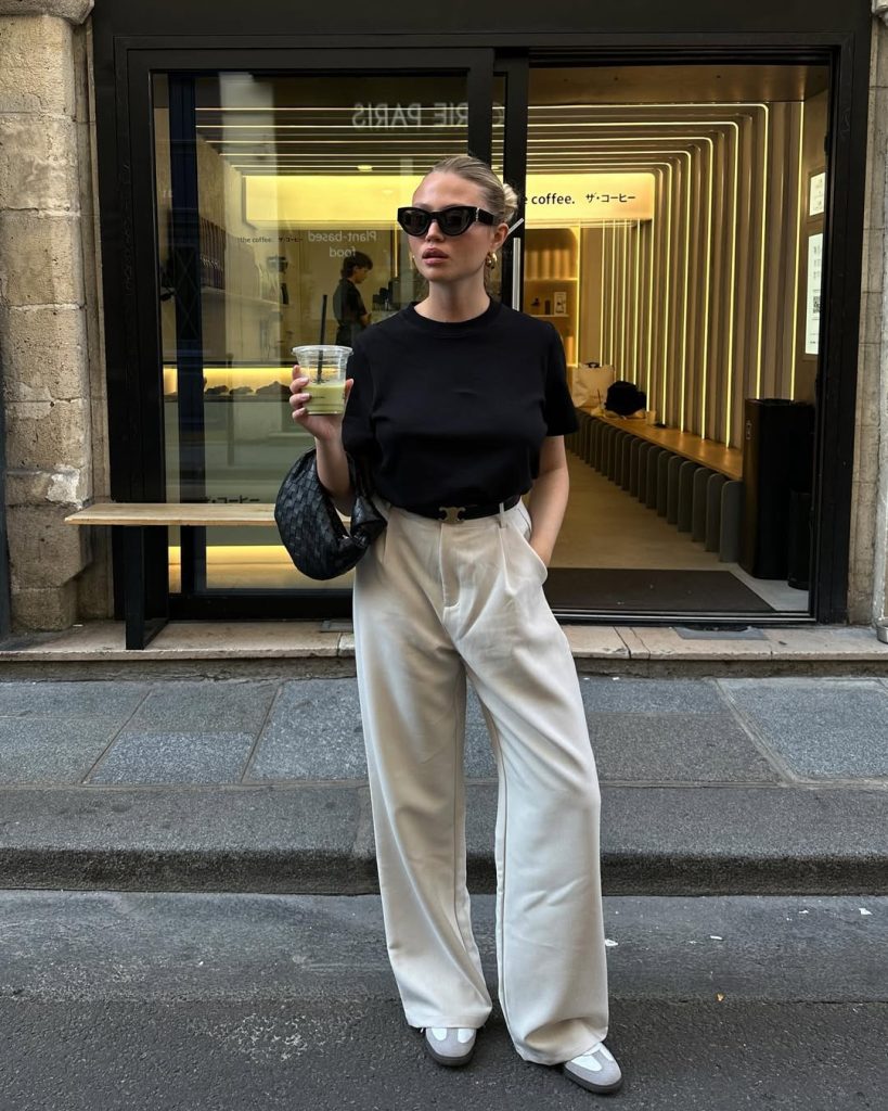 Minimalist summer work outfit with black fitted t-shirt, cream wide-leg trousers, statement sunglasses, designer shoulder bag and white sneakers