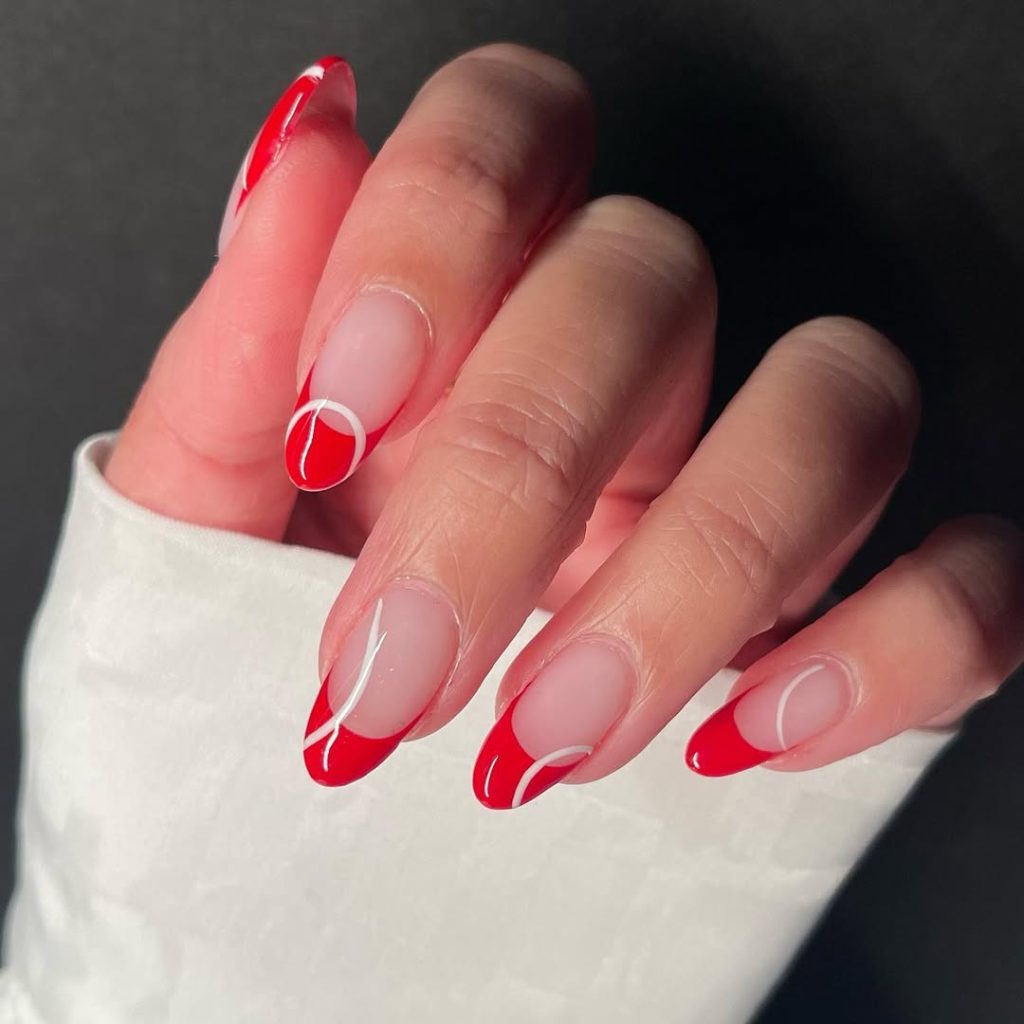 Almond shaped transparent nails with red French tips accented with white geometric circles and half-circles