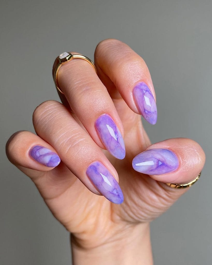 Long almond vacation nails with purple marble design and glossy finish
