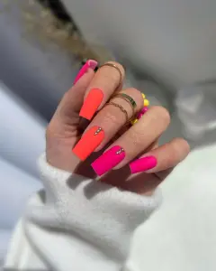 Long square neon matte nails in hot pink and coral with gold glitter triangles for vibrant summer style