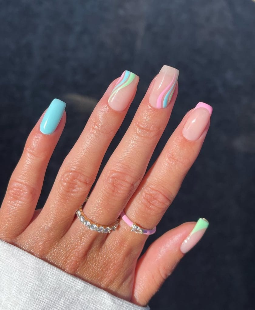 square vacation nails with pastel rainbow colors and striped accent designs
