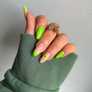 Almond neon lime green nails with nude base, green tips, and green with pink flower accents for vibrant summer style