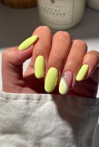 Long oval summer nails with bright lime green shimmer finish and clear accent nail with yellow lemon slice design
